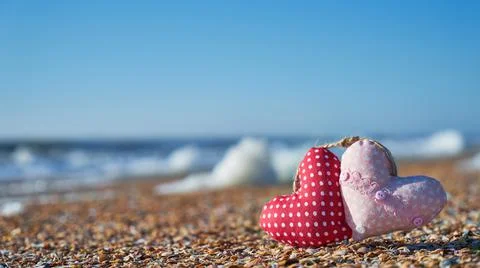 Image of a soft toy in the shape of a heart on the beach. Stock Photos