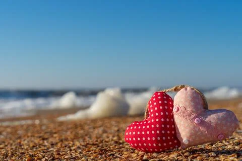 Image of a soft toy in the shape of a heart on the beach. Stock Photos