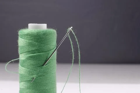 Image of a spool with a green thread and a needle. Stock Photos