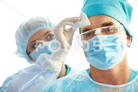 Image of surgeon during work with his forehead being rubbed by nurse Stock Photos