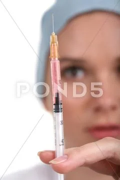 Image of syringe with vaccination in hand of physician looking at its needle Stock Photos