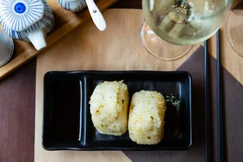 Image of tasty triangular onigiri from rice at black plate Stock Photos
