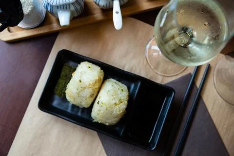 Image of tasty triangular onigiri from rice at black plate Stock Photos