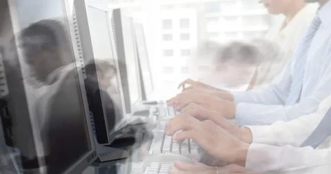 Image of team of colleagues typing on computer keyboards with people walking in Stock Photos