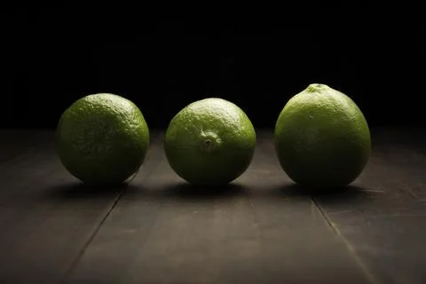 Image of three lemons close up on rustic wooden surface and black background Foto stock