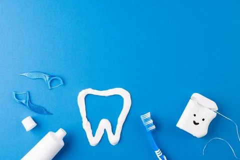 Image of toothbrush, toothpaste, string, liquid and tooth made of paste on blue Foto stock
