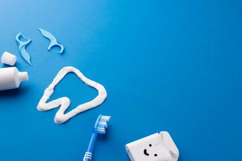 Image of toothbrush, toothpaste, string, liquid and tooth made of paste on blue Foto stock