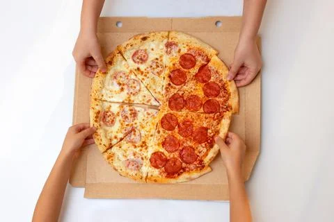 An image with a top view of children taking pizza slices out of a box on a white Stock Photos
