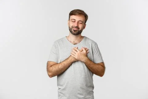 Image of touched bearded man in basic t-shirt, close eyes and holding hands on Stock Photos