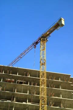 An image of a tower crane against the background of a house under constructio Stock Photos