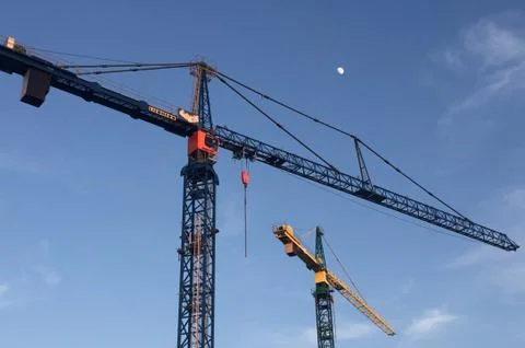 An image of two construction cranes silhouetted against a dark evening sky on Stock Photos