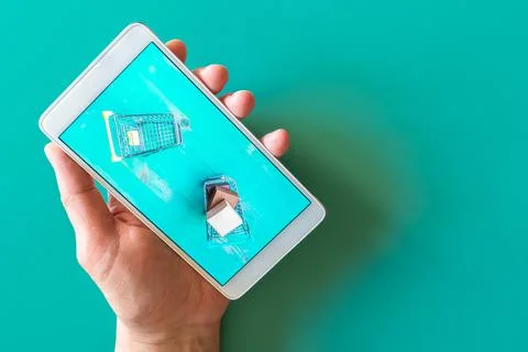 Image of two empty and full shopping carts in screen of phone holding in hand Stock Photos