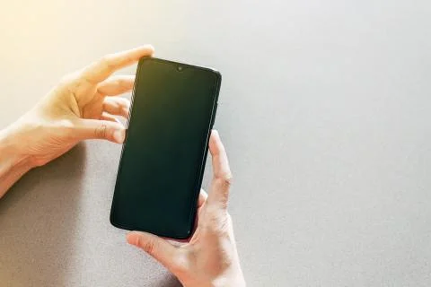 Image of two hands on a table holding a mobile phone Stock Photos