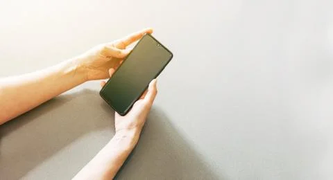 Image of two hands on a table holding a mobile phone Stock Photos