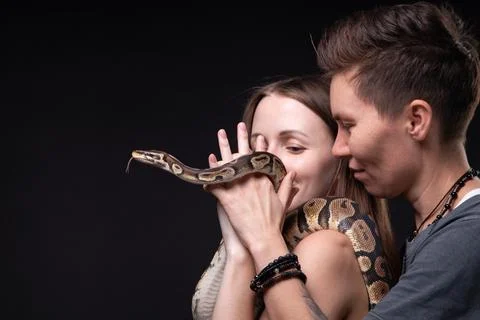 Image of two women with python on black background 写真素材