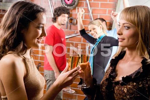 Image of two young women clink glasses during a disco Stock Photos
