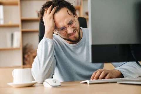 Image of unhappy bearded programmer man working with computer Stock Photos