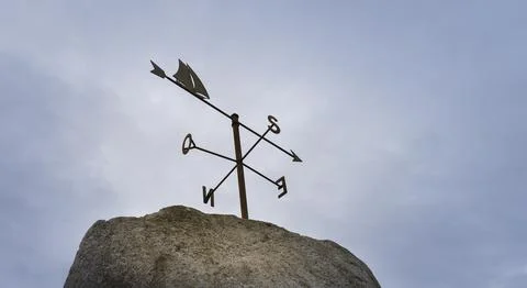 Image of a weather vane over a cloudy sky. Stock Photos