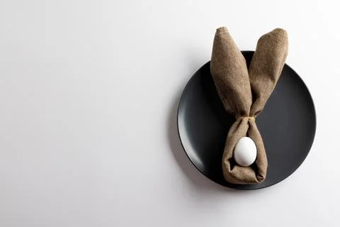 Image of white easter egg and bunny ears on black plate and copy space on white 库存照片