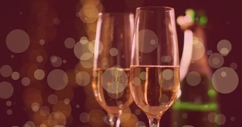 Image of white spots of light over two glasses of champagne Ilustração Stock