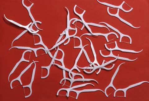 Image of white toothpicks with a thread on a red background. Stock Photos