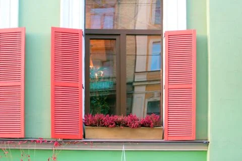 Image of window with red shutters and flowers on the windowsill Stock Photos