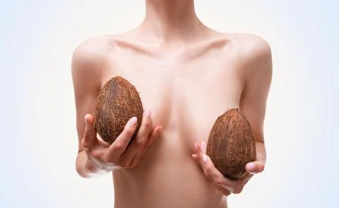 Image of a woman's breast covered with a coconut. Plastic surgery concept. .. Stock Photos