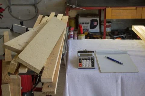 Image of a workbench in a workshop with a calculator, notepad and wooden boards Stock Photos