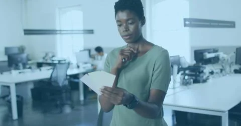 Image of world map and icons over african american woman working in office 库存照片