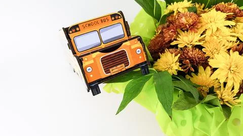 An image of a yellow school bus on a light background. a bouquet of flowers f Stock Photos