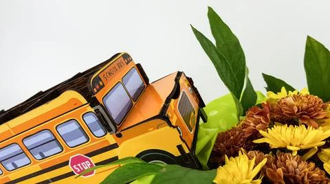 An image of a yellow school bus on a light background. a bouquet of flowers f Stock Photos