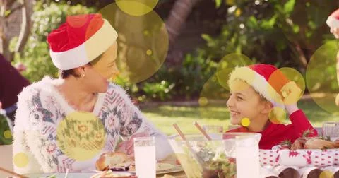 Image of yellow spots over caucasian family in santa hats at christmas table Stock Illustration