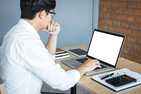 Image of Young man working in front of the laptop looking at screen with a cl Stock Photos