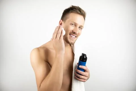 Image of young smiling man with white towel on his shoulder applying shaving Stock Photos