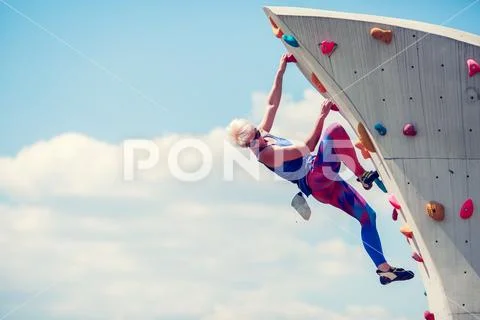 Image of young sportive woman clambering on rocky summer day Stock Photos