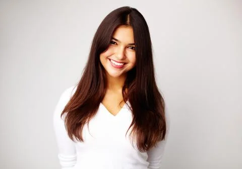 Image of young woman in white pullover smiling at camera Stock Photos
