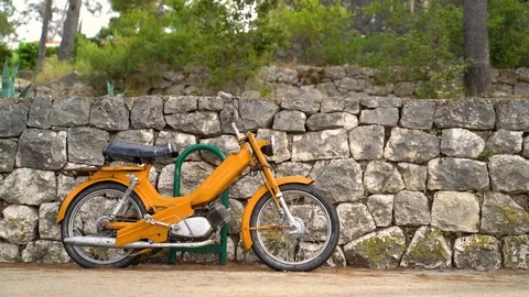Imagem of old yellow motorcycle in front of a stone wall, Croatia. Stock Footage 118085991