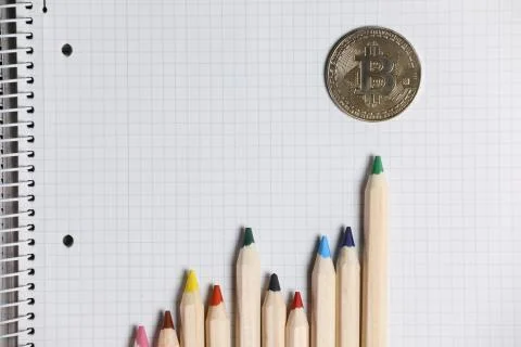 Imaginary bitcoin chart shown with color pencils on a white notebook. Stock Photos