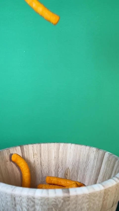 IMG Slow motion of cheese puffs falling into a wooden bowl, vertical Stock Footage 345154415