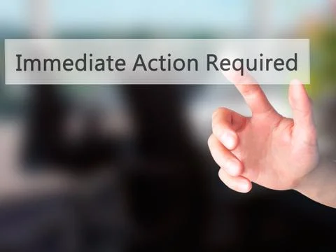 Immediate Action Required - Hand pressing a button on blurred background conc Stock Photos