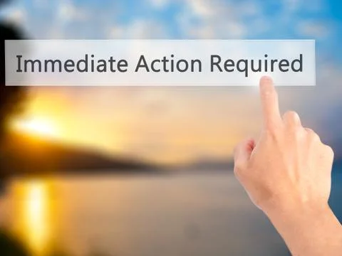Immediate Action Required - Hand pressing a button on blurred background conc Stock Photos