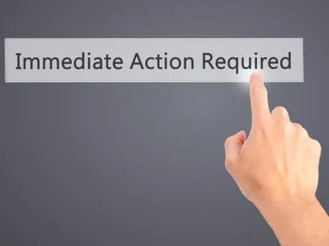 Immediate Action Required - Hand pressing a button on blurred background conc Stock Photos