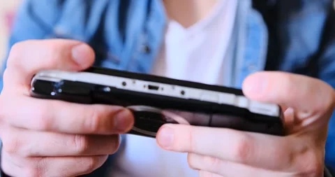 Immerse into gaming with a close-up of a man in a white tee and jeans playing a Stock Footage 274769956