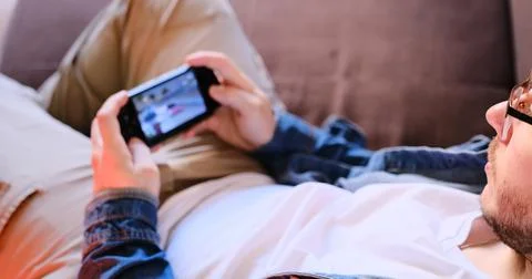 Immerse into gaming with a close-up of a man in a white tee and jeans playing a Stock Photos