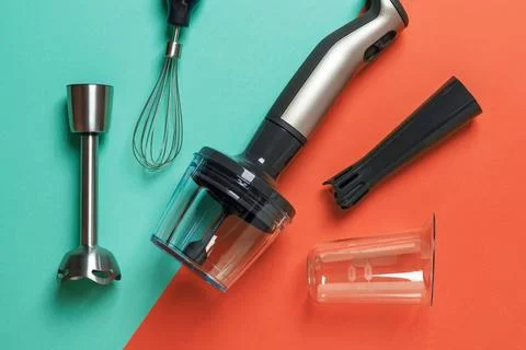 Immersion hand blender, different attachments and cups on a green red background Stock Photos