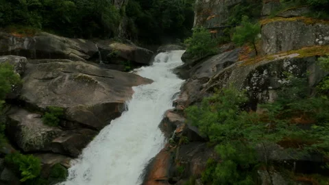 Immersive aerial perspective of a vigorous waterfall rushing through a rugged Stockbeeldmateriaal 336286943
