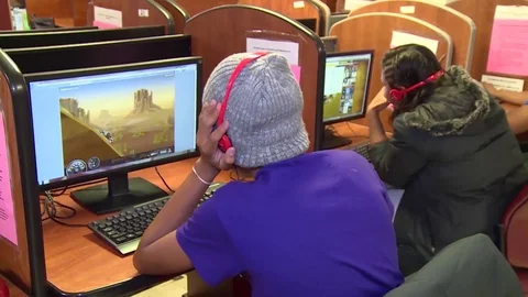 Immigrants playing games on computers at Texas residential immigration center Stock Footage 114555710
