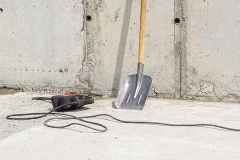 Impact drill with a flat chisel on a monolithic ceiling, a shovel stands against Stock Photos