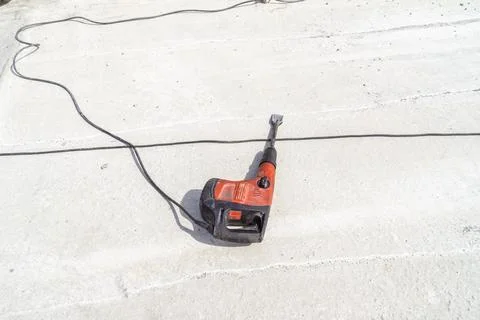 Impact drill with a nozzle flat chisel lies on the concrete surface of the ce Stock Photos