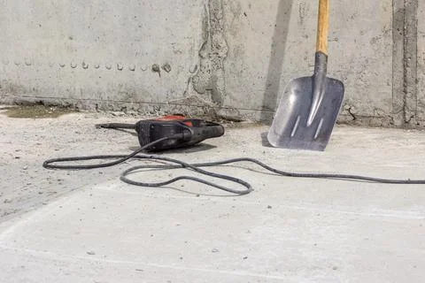 Impact drill with nozzle flat chisel lies on concrete surface of floor next t Stock Photos